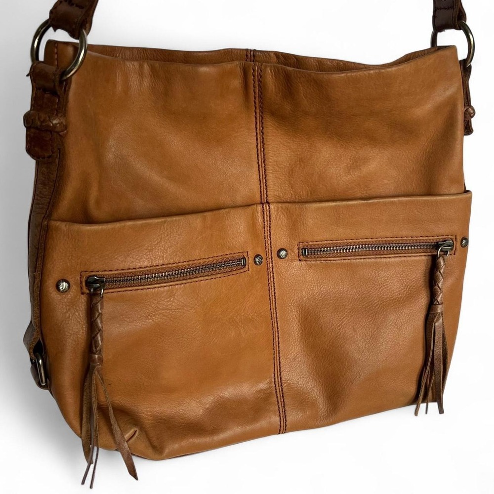 Tan leather shoulder bag with zipper closure, multiple pockets & braided tassel